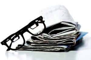 A pair of bioptic telescope glasses resting on a folded up newspaper